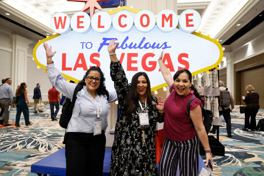 Three smiling women in front of the Las Vegas sign