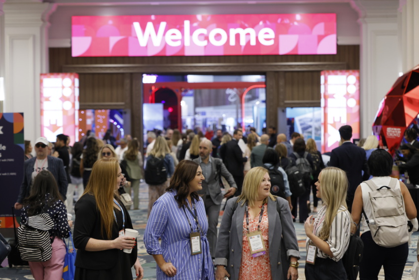 Show participants standing near the welcome sign at IMEX
